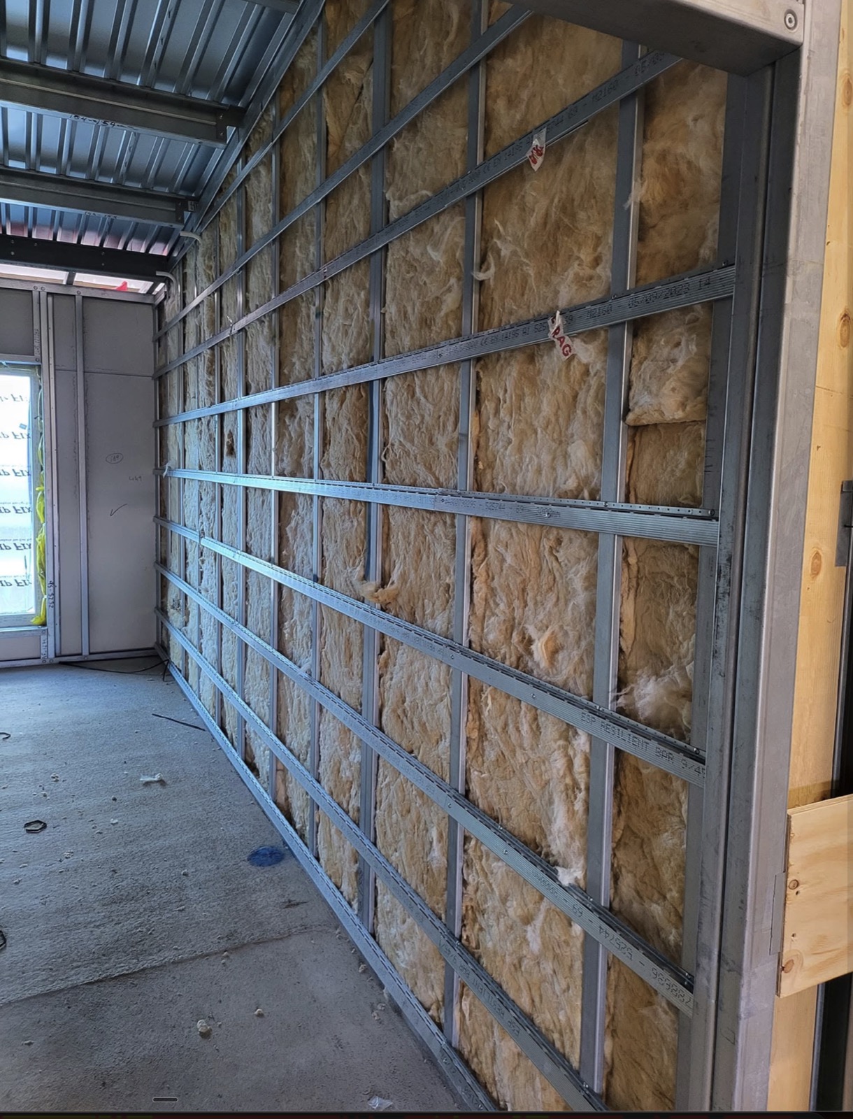Metal stud wall with acoustic insulation fitted between tracks
